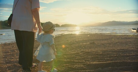 happy Asian Family Love mother holding Daughter hand and walking on the beach during Golden Hour Joy sunset together on Beachside, Share Precious Sunset Beach Moment