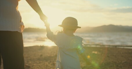 happy Asian Family Love mother holding Daughter hand and walking on the beach during Golden Hour Joy sunset together on Beachside, Share Precious Sunset Beach Moment