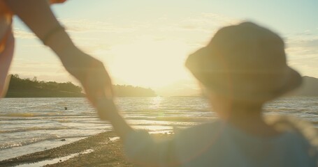 happy Asian Family Love mother holding Daughter hand and walking on the beach during Golden Hour...