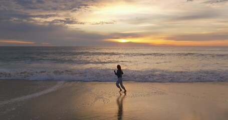 Aerial view. Beautiful woman barefoot are running In the ocean beach time evening amazing sunset, twilight