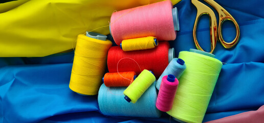 Multicolored fabric threads and scissors in the atelier at workplace