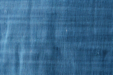 Blue denim fabric with a diagonal weave pattern slight sheen and a few small white specks scattered throughout.