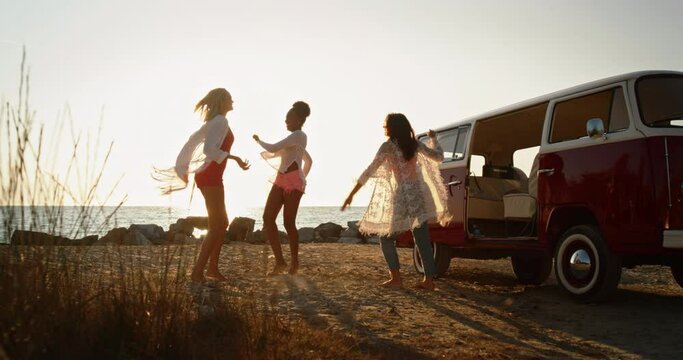 Contre Jour Shot: Slow Motion of Group of Young Female Friends Next to a Minivan, Celebrating Freedom and Dancing by the Sea. Multiethnic Women Having Fun, Enjoying Their Youth and Summer Days