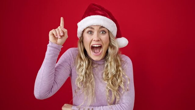 Young blonde woman wearing christmas hat with idea expression over isolated red background