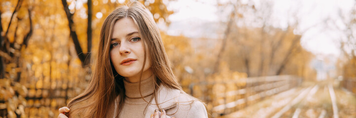 beautiful long-haired woman walks through the autumn streets. Railway, autumn, woman in a coat.