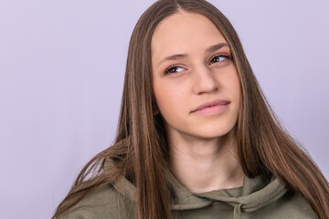 Studio portrait of girl in casual clothes looking with dreamful expression. Gray background