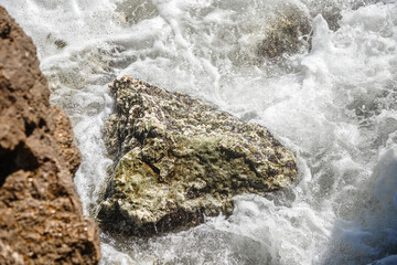 The waves break on the rocks. Rocky shore. The coastline. The power of the elements. The raging sea.