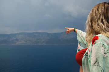 Curvy girl on a sea cruise looking at the mountains and the impending thunderstorm