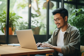 Business Asian man in casual wear laptop while working on laptop at home office. Young man freelancer online working, telecommuting.