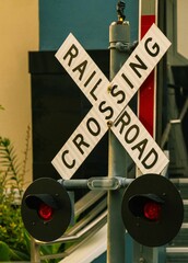 railroad crossing sign hanging from a post next to an escalator