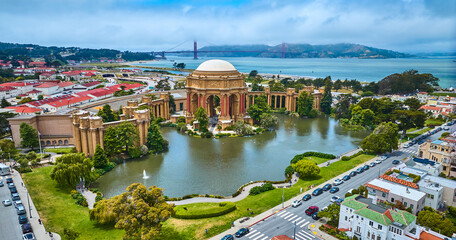 Aerial full view Palace of Fine Arts lagoon and colonnade pillars with Golden Gate Bridge