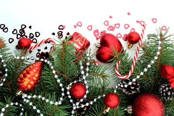 Christmas tree toys and spruce branches lie on a white background.