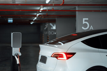 EV electric car recharge at shopping center parking lot charging in downtown city showing urban...