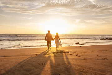 Romantic couple strolling barefoot on the beach during sunset