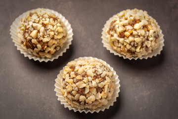 Peanuts and other Brigadeiro nuts, a traditional Brazilian dessert, piled on a white ceramic plate on a marble surface.
