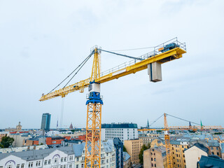 Fototapeta na wymiar Yellow construction tower crane at a construction site