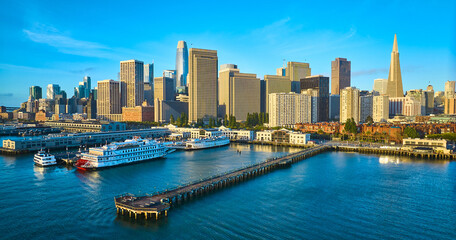 Aerial Pier 7 at sunrise with San Francisco skyscraper skyline and boats docked in bay