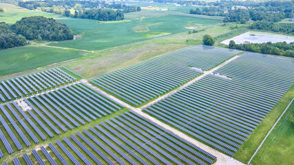 Solar panels facing straight up in aerial over solar farm with swamp and farmland around it