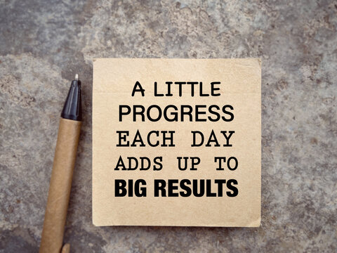 Motivational and inspirational wording. A LITTLE PROGRESS EACH DAY ADDS UP TO BIG RESULTS written on a notepad. With blurred styled background.
