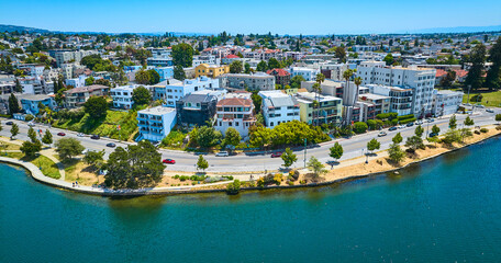 Obraz na płótnie Canvas Oakland aerial of residential area with road along lakeshore and blue sky