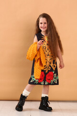 little model girl with long brown hair in designer floral dress, yellow jacket and military boots
