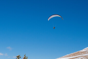 Fototapeta na wymiar Tandem Paraglider soaring over Grand Teton National Park from Rendezvous Peak in Jackson Hole, Wyoming