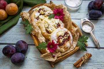 Sweet bun with plums on a rustic wooden tray