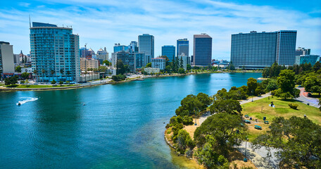Lake Merritt aerial with boats on water and skyscrapers across the way from small waterfront park