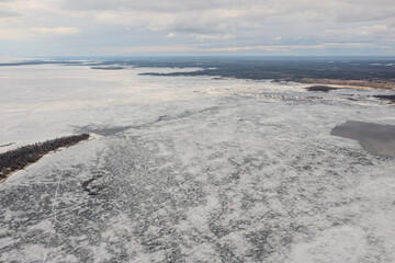 A mesmerizing view of a frozen Lake Simcoe, its icy expanse glistening under the winter sun, creating a stunning winter scene.