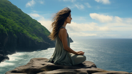 Woman meditating on top of rock by the seashore - obrazy, fototapety, plakaty