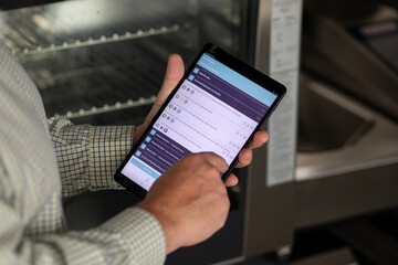 Chef Using iPad in Commercial Kitchen for Audit - obrazy, fototapety, plakaty