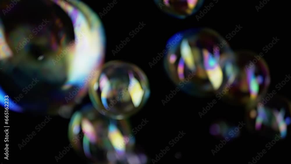 Poster lot of large colorful soap bubbles fly on a black background in empty space. blowing. falling. splas