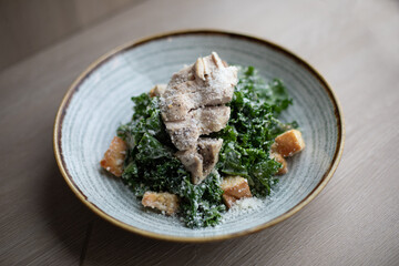 Sous Vide Chicken Over Kale Caesar Salad in a Light Blue Bowl