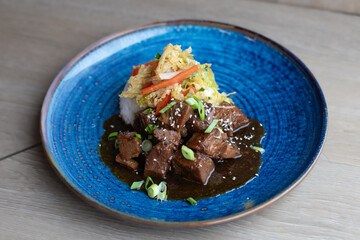 Sous Vide Braised Beef with Rice and Slaw on a Dark Blue Plate