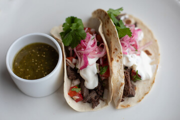 Sous Vide Pork Soft Shell Tacos with Pickled Red Onion and Sour Cream on a White Plate