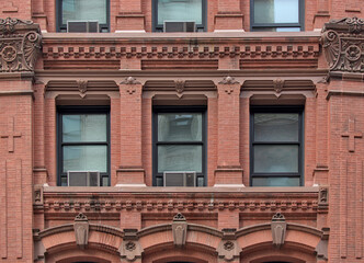 three windows with cornice detail in old historic commercial and residential red brick building in the east village neighborhood of manhattan, new york city (close up of facade architecture) © Yuriy T