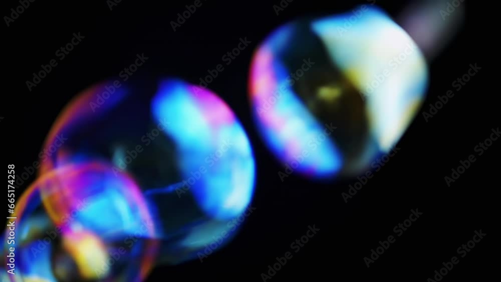 Poster colorful soap bubbles fly in an empty space on isolated black background. many large, small rainbow 