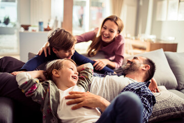 Happy young family relaxing on the couch together at home - Powered by Adobe