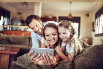Foto op Aluminium Happy young family looking at the smartphone on the couch at home © Geber86