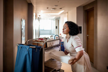 Hotel maid taking towels from a cleaning cart for the room