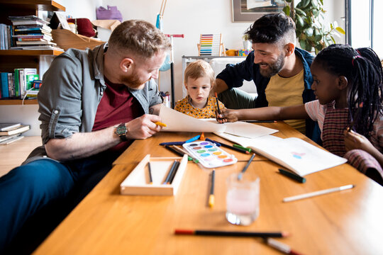 Male gay couple drawing with their adopted children at home