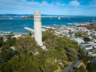 Fototapeta na wymiar Aerial Coit Tower atop Telegraph hill with Oakland Bay Bridge in the bay