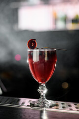 Red alcoholic drink with berries and Pastille in old fashioned glass on blurred background