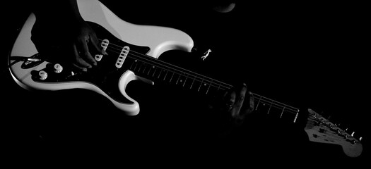Guitarrista tocando sua guitarra branca em show em preto e branco.  