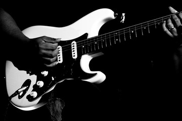 Guitarrista tocando sua guitarra branca em show em preto e branco.   - obrazy, fototapety, plakaty