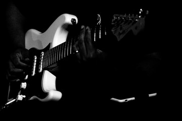 Guitarrista tocando sua guitarra branca em show em preto e branco.  