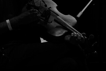Violinista tocando o seu violino em preto e branco no escuro.