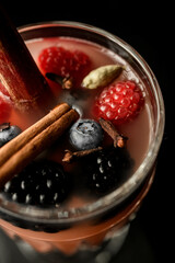 Tasty fragrant berries cocktail in transparent glass, decorated with cinnamon stick and fresh berries at the bar counter