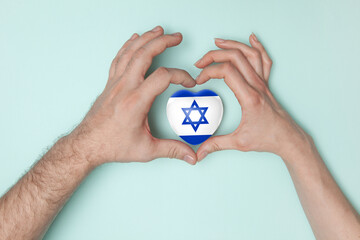 Heart with print of Israel flag in female and male hands.. Flat lay.