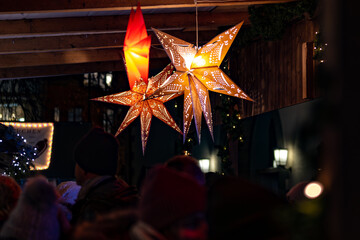 Closeup of visitors of the beautifully decorated Christmas market with a bright shining...